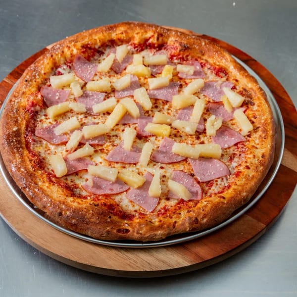 A New York Vinny's Pizza with ham and pineapple on a wooden serving board.