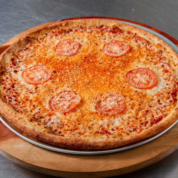 A New York Vinny's Pizza with melted cheese, tomato slices, and parmesan on a wooden board.