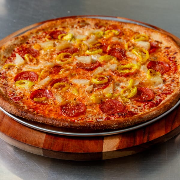 New York Vinny's Pizza with pepperoni, pineapple, and banana peppers on a wooden board.